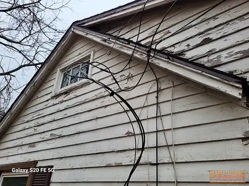 Close-up of loose service entrance cable mounting hardware showing rust and deterioration at Raytown home
