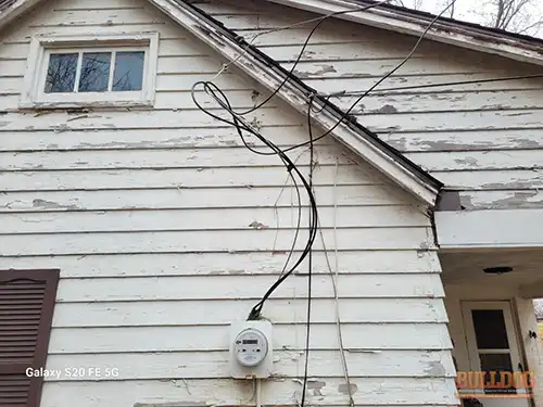 Front view of loose service entrance cables at Raytown residence showing electrical service defect from street perspective