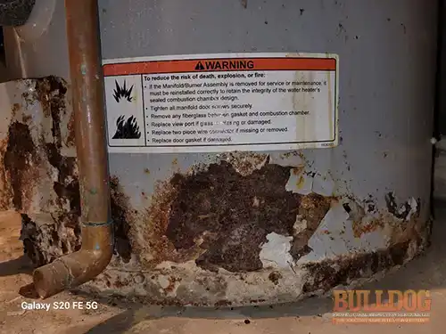 rusted-out-water-heater-polo-mo-4311-sw-state-rte-t-64671-39.59336100N-94.07731600W-bulldog-home-inspections-20251202_151449 Close-up of severely rusted water heater - Polo, MO inspection - December 2025
