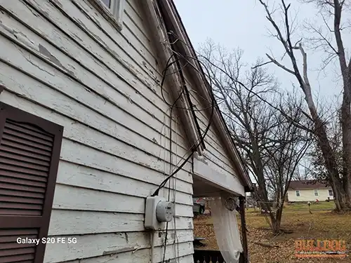 Service entrance cables loose at siding attachment point in Raytown showing gap between cable and exterior wall